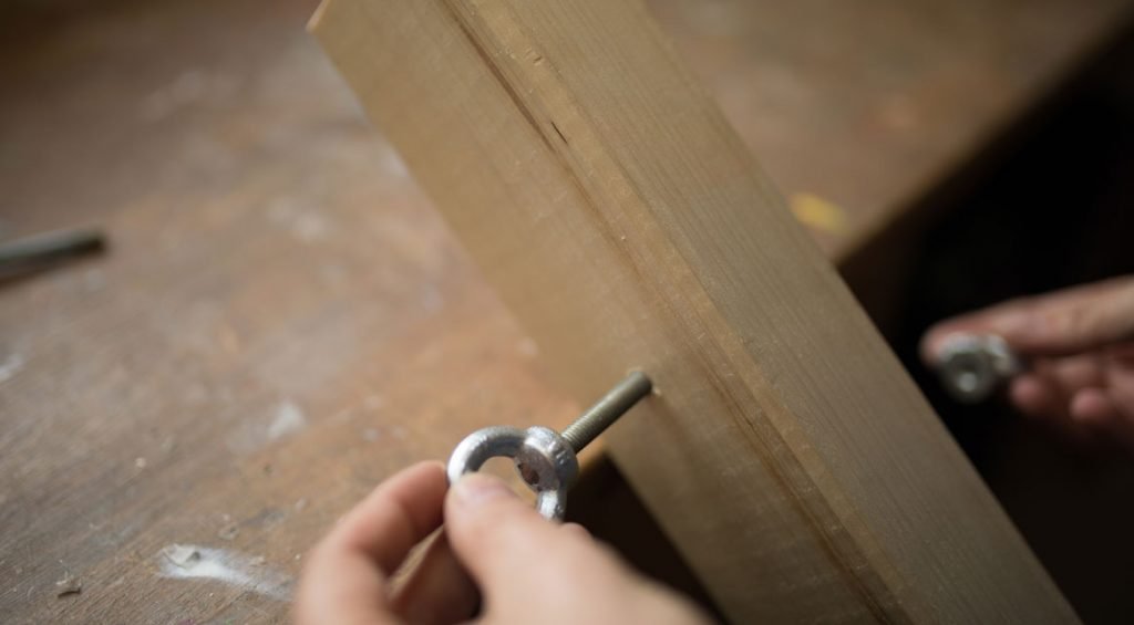 Put one bolt through the borehole, which points outwards until the head disappears into the lowering. Then turn one eyelet onto the thread.